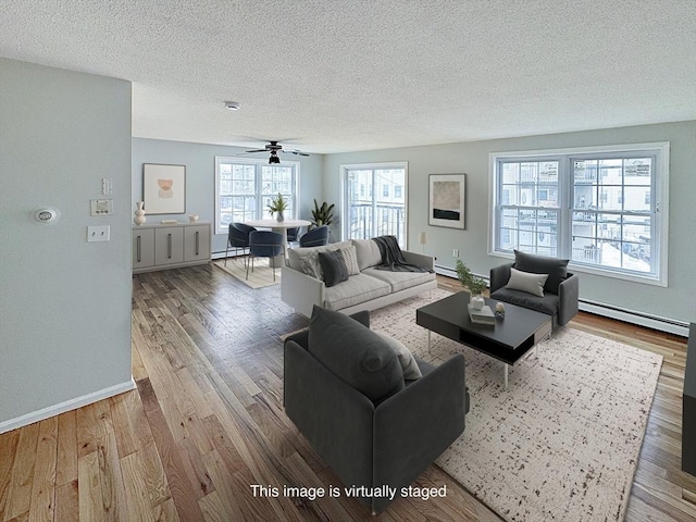 living room with a textured ceiling, baseboard heating, a baseboard radiator, and wood finished floors