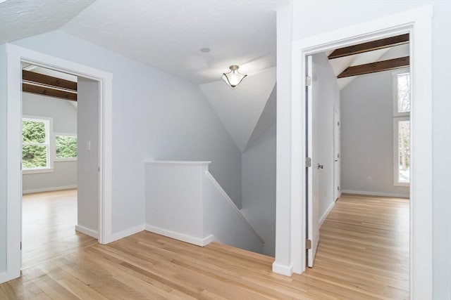 hall featuring light hardwood / wood-style flooring and lofted ceiling with beams