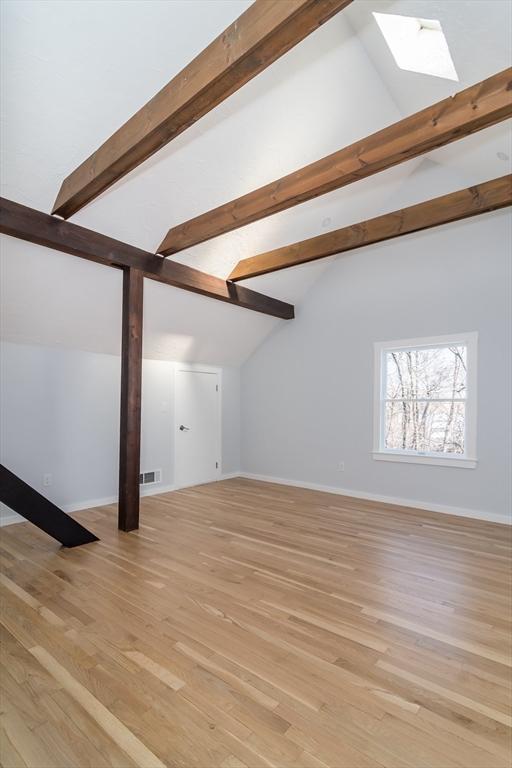 additional living space featuring lofted ceiling with skylight and light hardwood / wood-style flooring