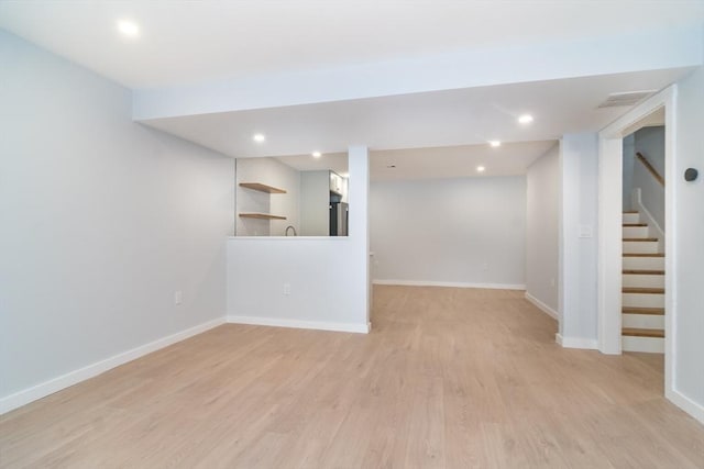 basement featuring refrigerator and light hardwood / wood-style flooring