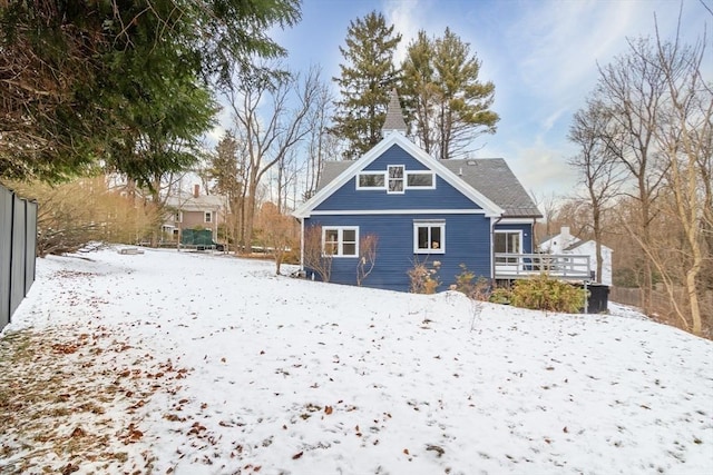 snow covered rear of property with a wooden deck