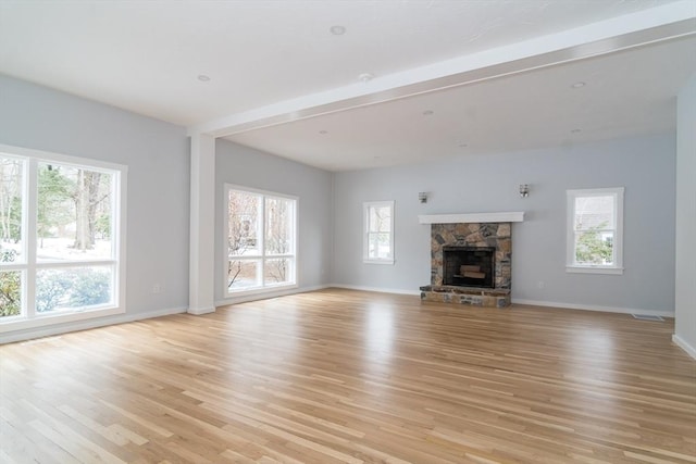 unfurnished living room featuring light hardwood / wood-style floors and a stone fireplace