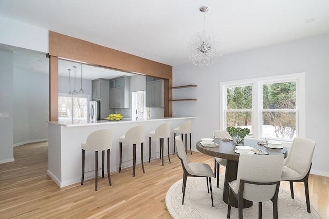 dining space with light hardwood / wood-style floors and a chandelier