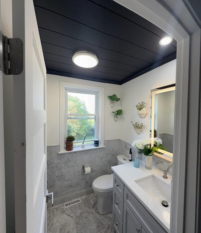 5 Cortland Dr, Hudson, MA 01749 - bathroom featuring wainscoting, toilet, vanity, wooden ceiling, and marble look tiles