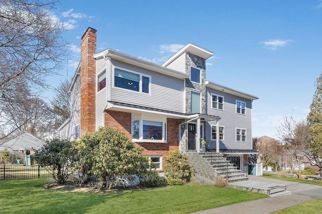 view of front of house with a front yard, fence, brick siding, and a chimney