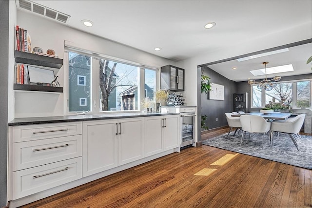 kitchen featuring visible vents, open shelves, a skylight, dark wood-type flooring, and dark countertops