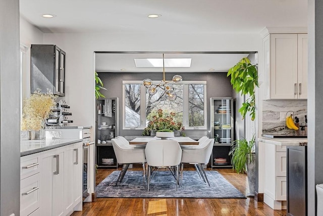 dining area featuring wood finished floors, recessed lighting, wine cooler, a skylight, and a chandelier