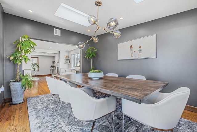 dining room with visible vents, baseboards, recessed lighting, a skylight, and wood finished floors