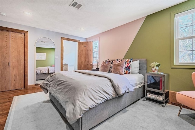 bedroom with light wood-type flooring, visible vents, a textured ceiling, and recessed lighting