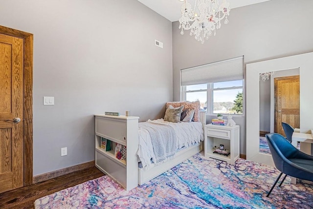 bedroom featuring a notable chandelier, visible vents, baseboards, and wood finished floors