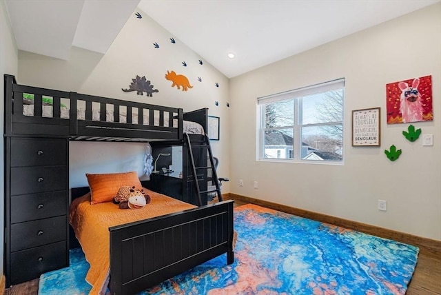 bedroom with vaulted ceiling, wood finished floors, and baseboards