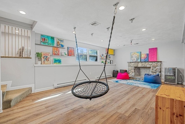 playroom featuring wood finished floors, visible vents, baseboard heating, and baseboards