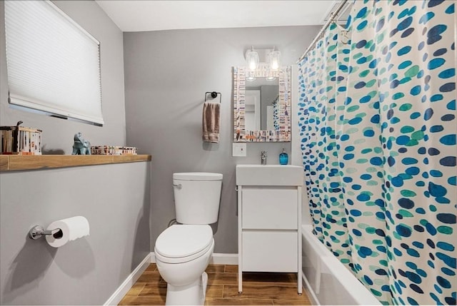 bathroom featuring wood finish floors, shower / bathtub combination with curtain, toilet, baseboards, and vanity