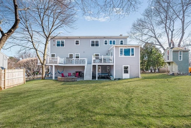 rear view of property featuring a lawn, a wooden deck, stairs, and fence