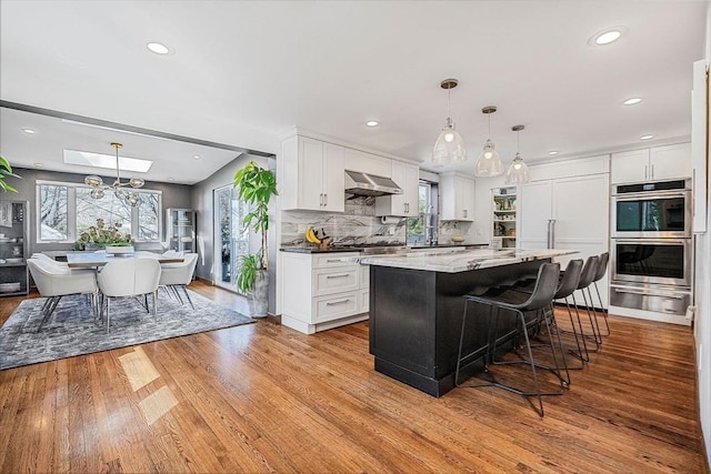 kitchen featuring decorative backsplash, white cabinets, appliances with stainless steel finishes, and ventilation hood