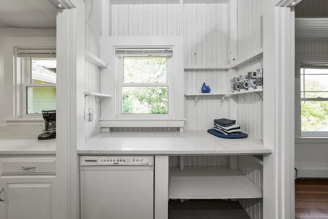 kitchen with dishwasher, light stone counters, wood-type flooring, white cabinets, and wood walls