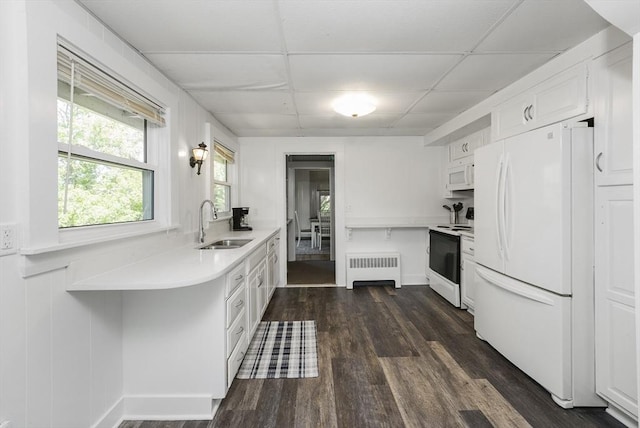 kitchen with sink, radiator, white cabinets, white appliances, and a drop ceiling