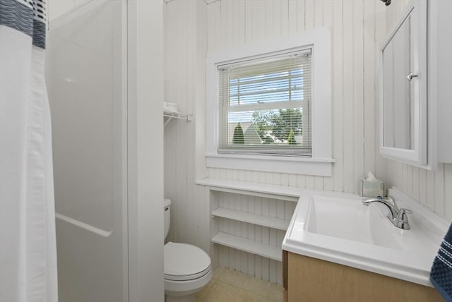 bathroom with tile patterned flooring, vanity, wooden walls, and toilet