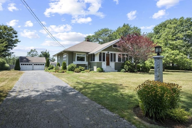 view of front facade with an outbuilding, a garage, and a front lawn