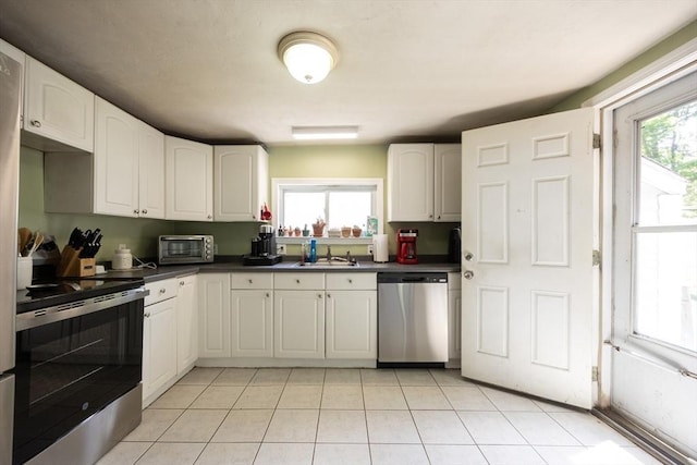 58 Howland St, Marlborough, MA 01752 - kitchen with stainless steel appliances, dark countertops, a sink, white cabinetry, and healthy amount of natural light