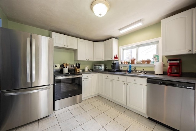 58 Howland St, Marlborough, MA 01752 - kitchen featuring stainless steel appliances, a sink, dark countertops, and light tile patterned floors