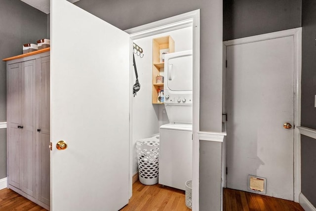 washroom with laundry area, wood finished floors, and stacked washer and clothes dryer