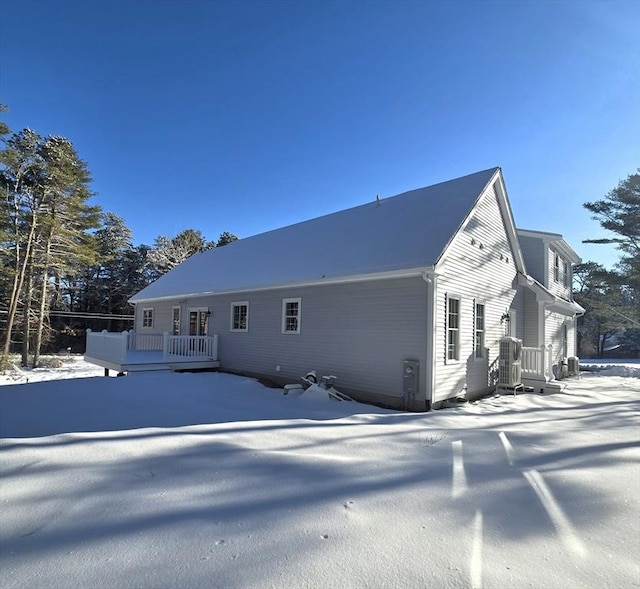 snow covered rear of property with a deck