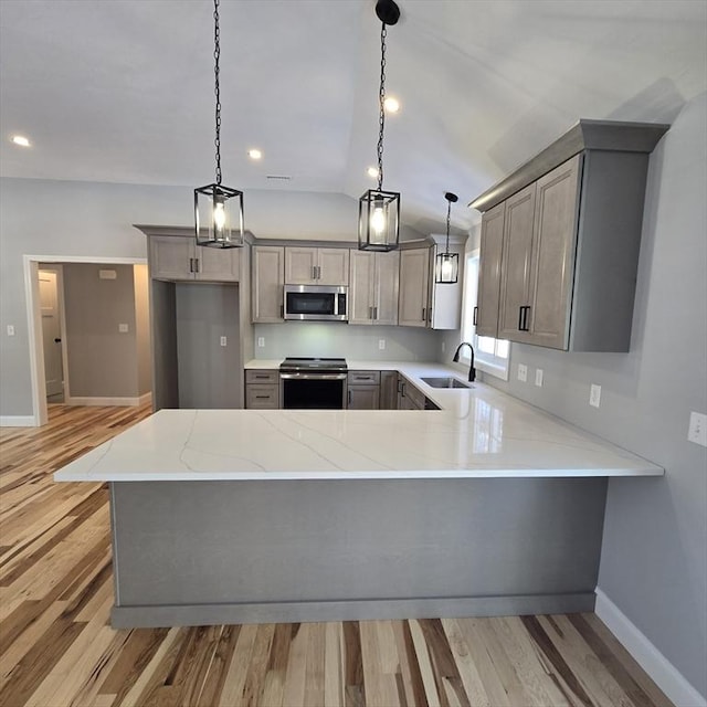 kitchen featuring hanging light fixtures, stainless steel appliances, sink, and kitchen peninsula