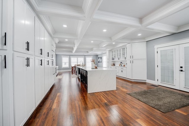 kitchen featuring white cabinets, a center island, dark wood-type flooring, beamed ceiling, and coffered ceiling