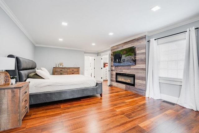 bedroom featuring ornamental molding, a fireplace, and hardwood / wood-style floors