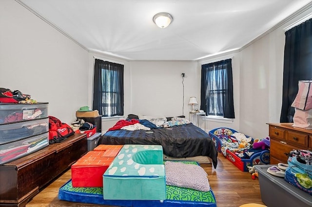 bedroom featuring wood finished floors, crown molding, and multiple windows