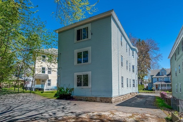rear view of house featuring asphalt driveway and fence