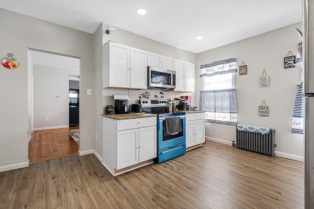 kitchen with stainless steel appliances, radiator heating unit, white cabinetry, light wood-type flooring, and recessed lighting