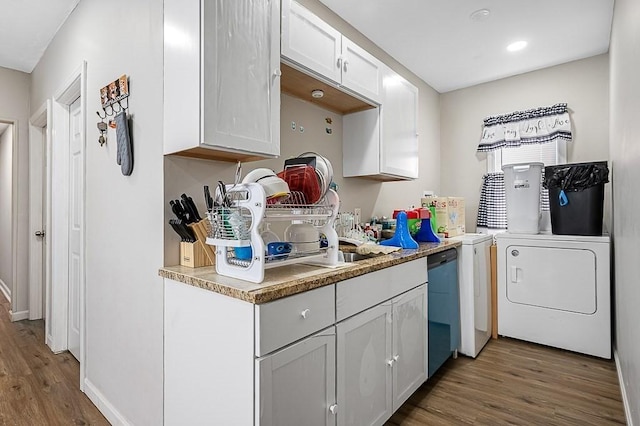 kitchen with washer / dryer, wood finished floors, dishwasher, white cabinetry, and baseboards