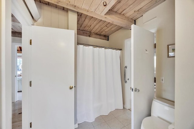 bathroom with tile patterned flooring, a shower with curtain, toilet, beam ceiling, and wood ceiling
