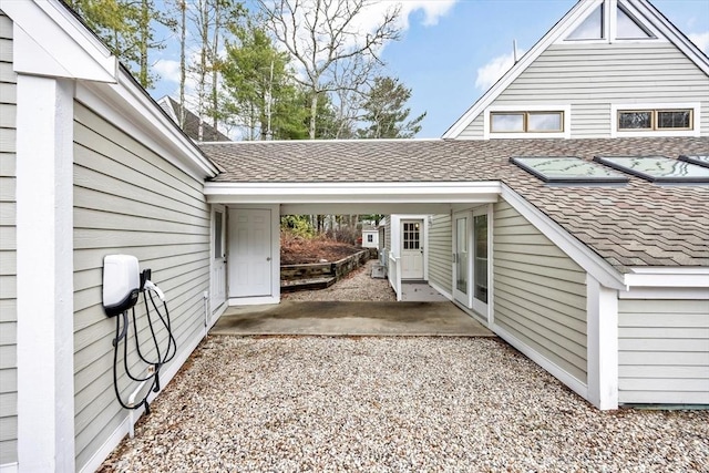 view of home's exterior with roof with shingles, a patio area, and a carport