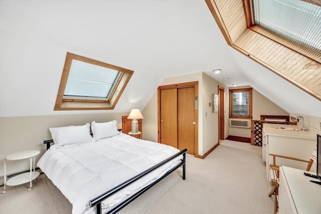 bedroom featuring baseboard heating, a closet, light carpet, lofted ceiling with skylight, and a sink