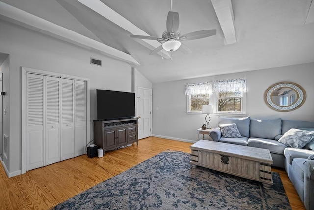 living room with ceiling fan, visible vents, vaulted ceiling with beams, and light wood-type flooring