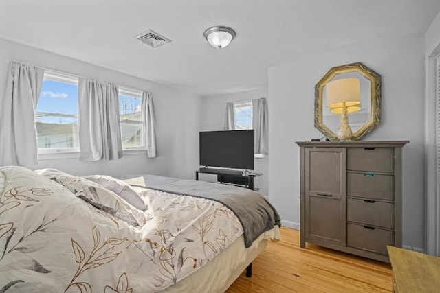 bedroom with baseboards, light wood-style flooring, and visible vents