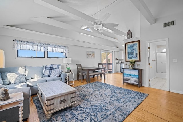 living room with visible vents, wood finished floors, baseboards, vaulted ceiling with beams, and a ceiling fan