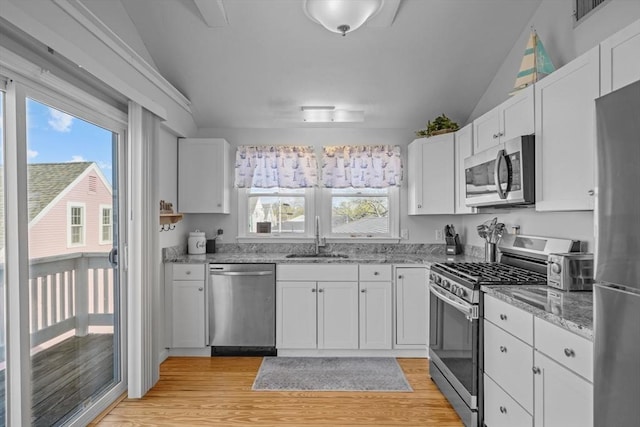 kitchen with stainless steel appliances, vaulted ceiling, a wealth of natural light, and a sink