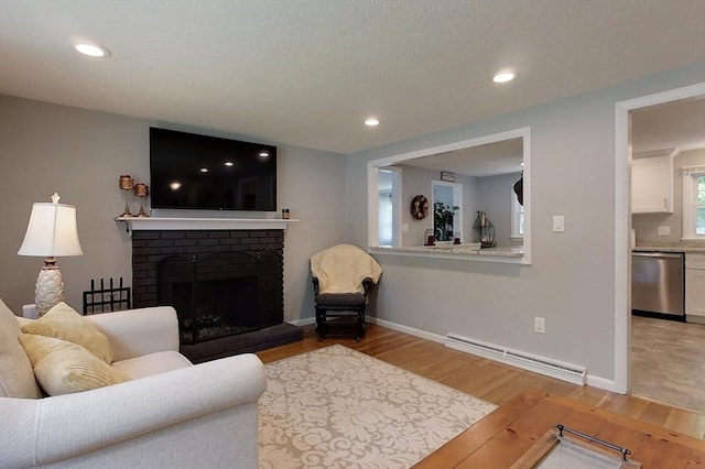 12 Pine St, Pepperell, MA 01463 - living room with a baseboard radiator, light wood-style floors, a brick fireplace, and recessed lighting