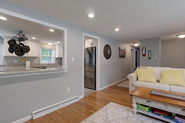 12 Pine St, Pepperell, MA 01463 - living room with a baseboard radiator, light wood-style flooring, recessed lighting, and a textured ceiling