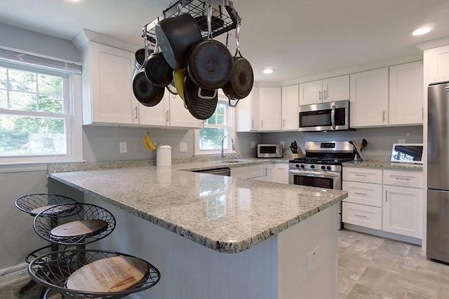 12 Pine St, Pepperell, MA 01463 - kitchen with stainless steel appliances, white cabinetry, a breakfast bar area, a peninsula, and recessed lighting