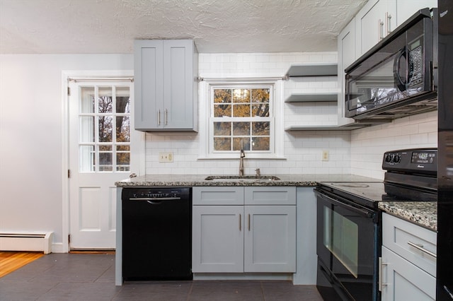 kitchen featuring gray cabinetry, sink, a baseboard radiator, dark stone countertops, and black appliances