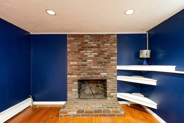 unfurnished living room featuring hardwood / wood-style floors, a textured ceiling, a fireplace, and a baseboard heating unit