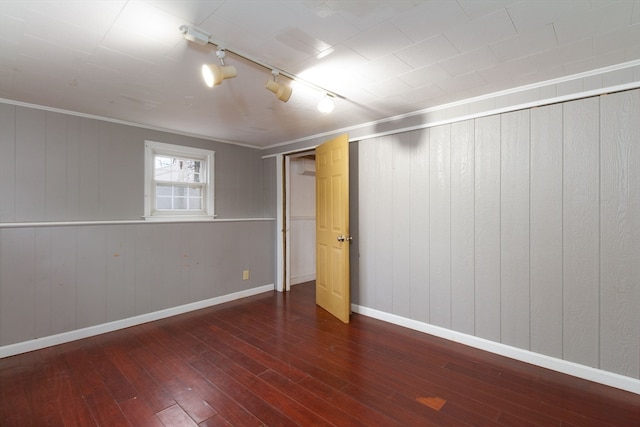 basement featuring crown molding, dark hardwood / wood-style flooring, and rail lighting