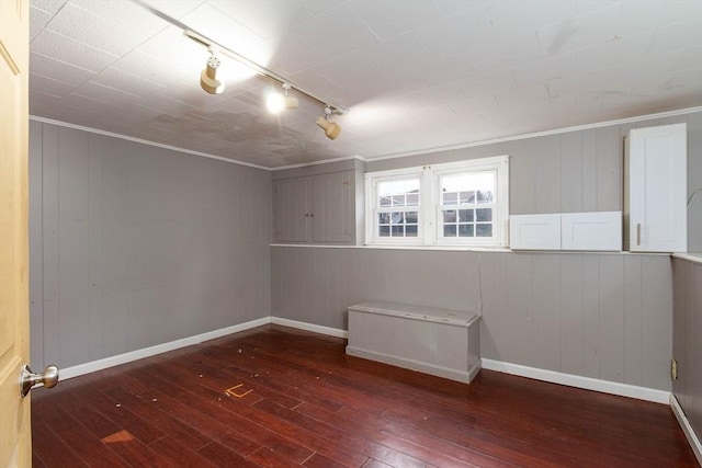 spare room with crown molding, rail lighting, and dark hardwood / wood-style floors