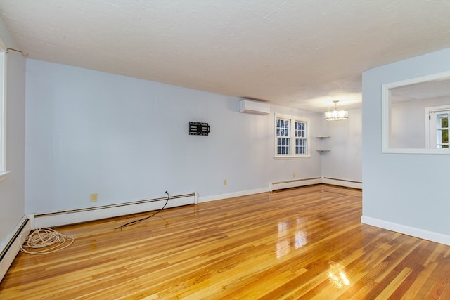 unfurnished room with an AC wall unit, hardwood / wood-style flooring, and a baseboard heating unit