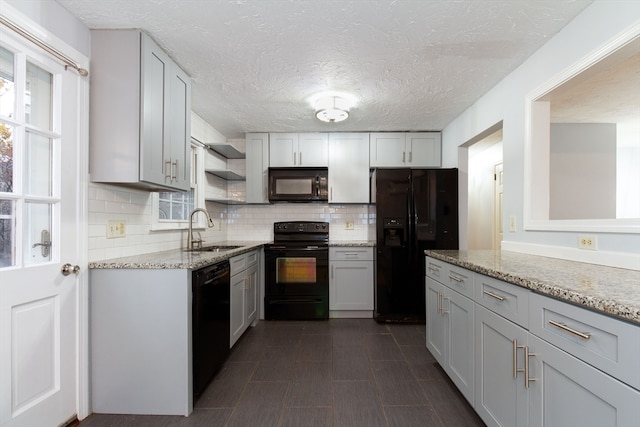 kitchen featuring decorative backsplash, sink, light stone countertops, and black appliances